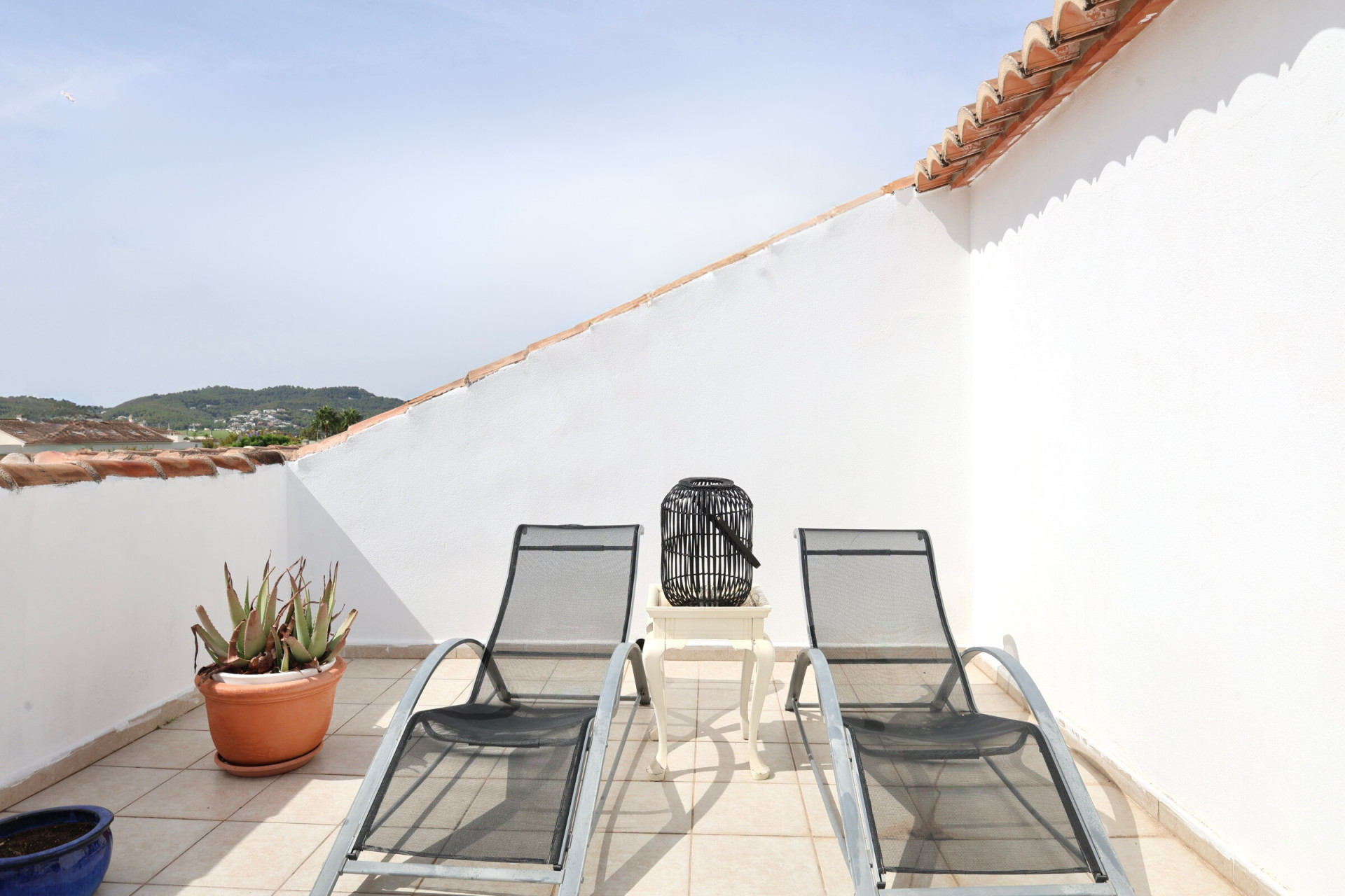 Terrasse avec deux chaises longues en métal, table d'appoint et vue sur la montagne.