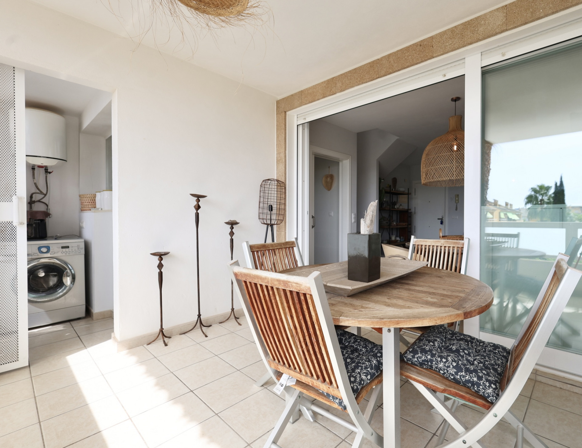 Terrasse avec table ronde en bois et chaises assorties, avec accès à une buanderie.