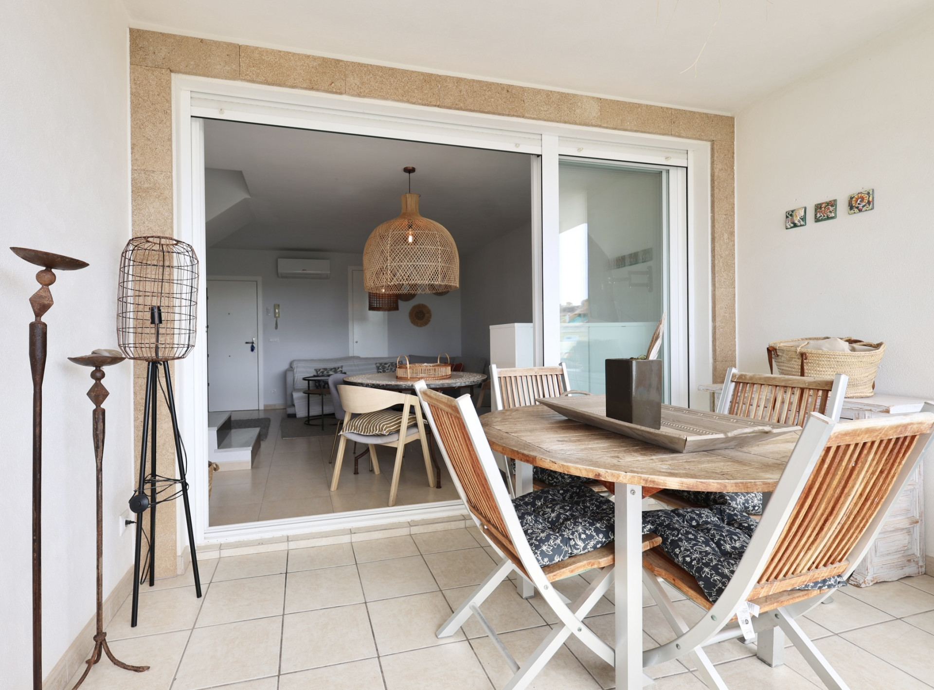 Terrasse couverte avec table en bois et chaises pliantes à coussins à motifs.