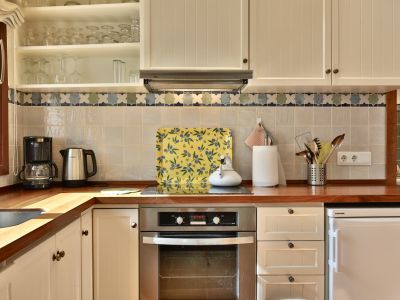 Coin cuisine avec plan de travail en bois, placards crème, four intégré et crédence carrelée à motif décoratif.