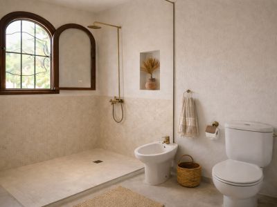 Salle de bain lumineuse avec douche à l'italienne carrelée de mosaïque beige. Fenêtre arquée en bois, robinetterie en laiton et murs texturés.