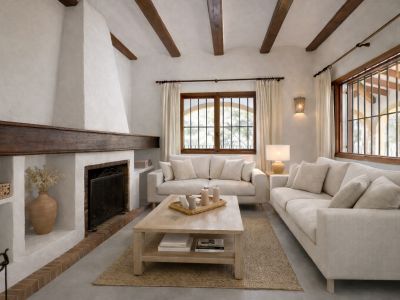 Salon avec une cheminée traditionnelle en stuc blanc et un manteau en bois foncé. Les poutres apparentes au plafond et les fenêtres à barreaux en bois ajoutent au caractère.