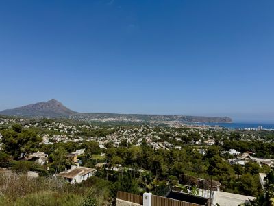 Vue panoramique sur Jávea, englobant le Montgó, la mer Méditerranée et le paysage urbain verdoyant sous un ciel dégagé.