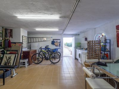 Pièce utilitaire polyvalente avec lave-linge, sèche-linge, évier et étagères de rangement. Dotée d'un sol carrelé, d'un éclairage fluorescent et d'un accès extérieur direct.