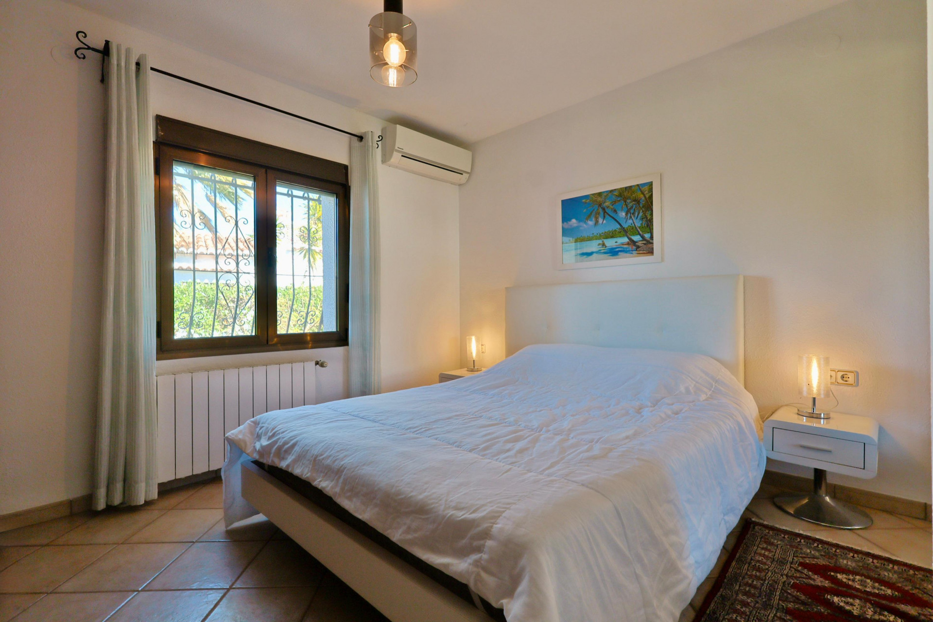 Chambre lumineuse avec lit double, tables de chevet modernes et fenêtre avec vue sur l'extérieur.