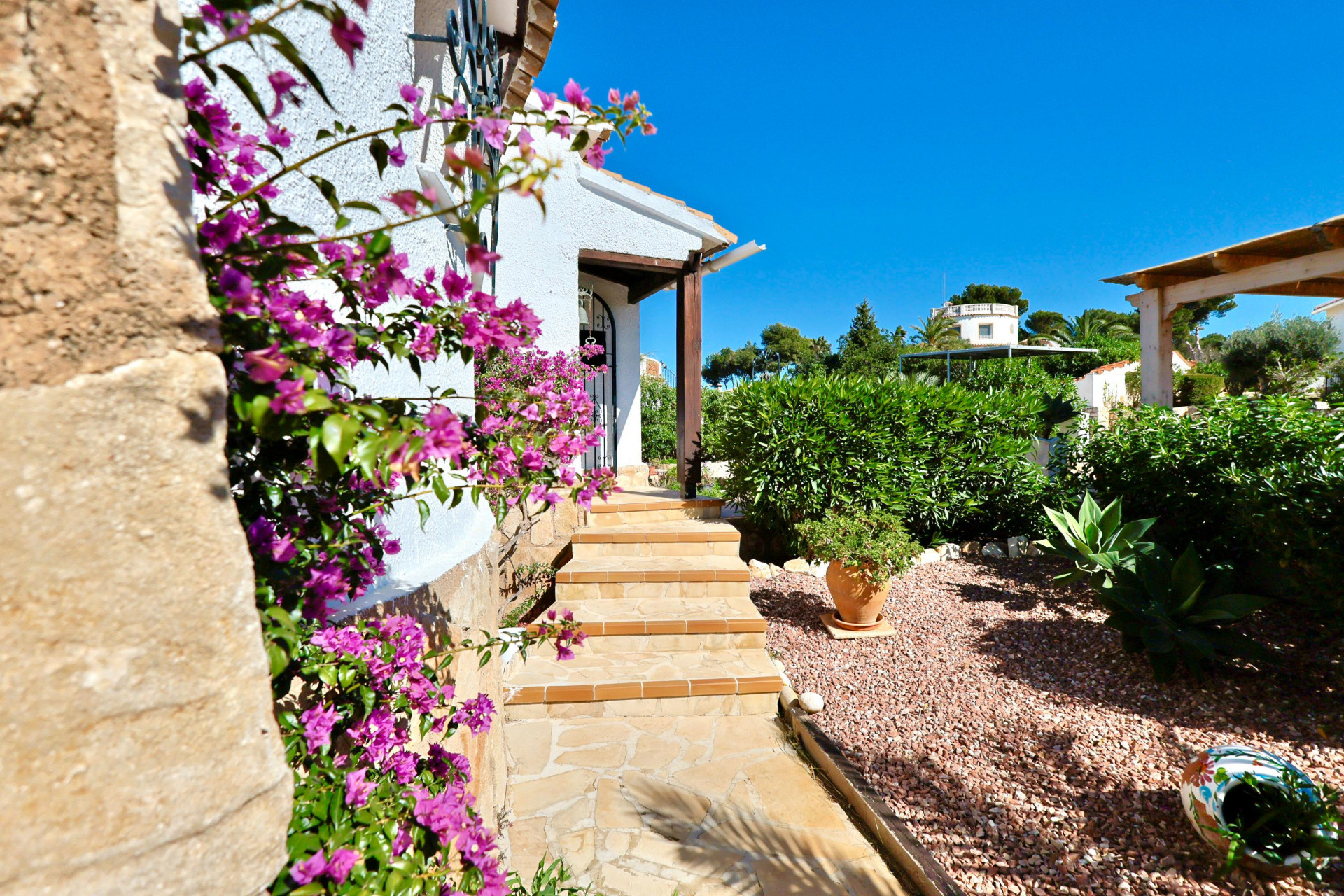 Entrée de la villa avec bougainvilliers fuchsias et jardin de gravier.