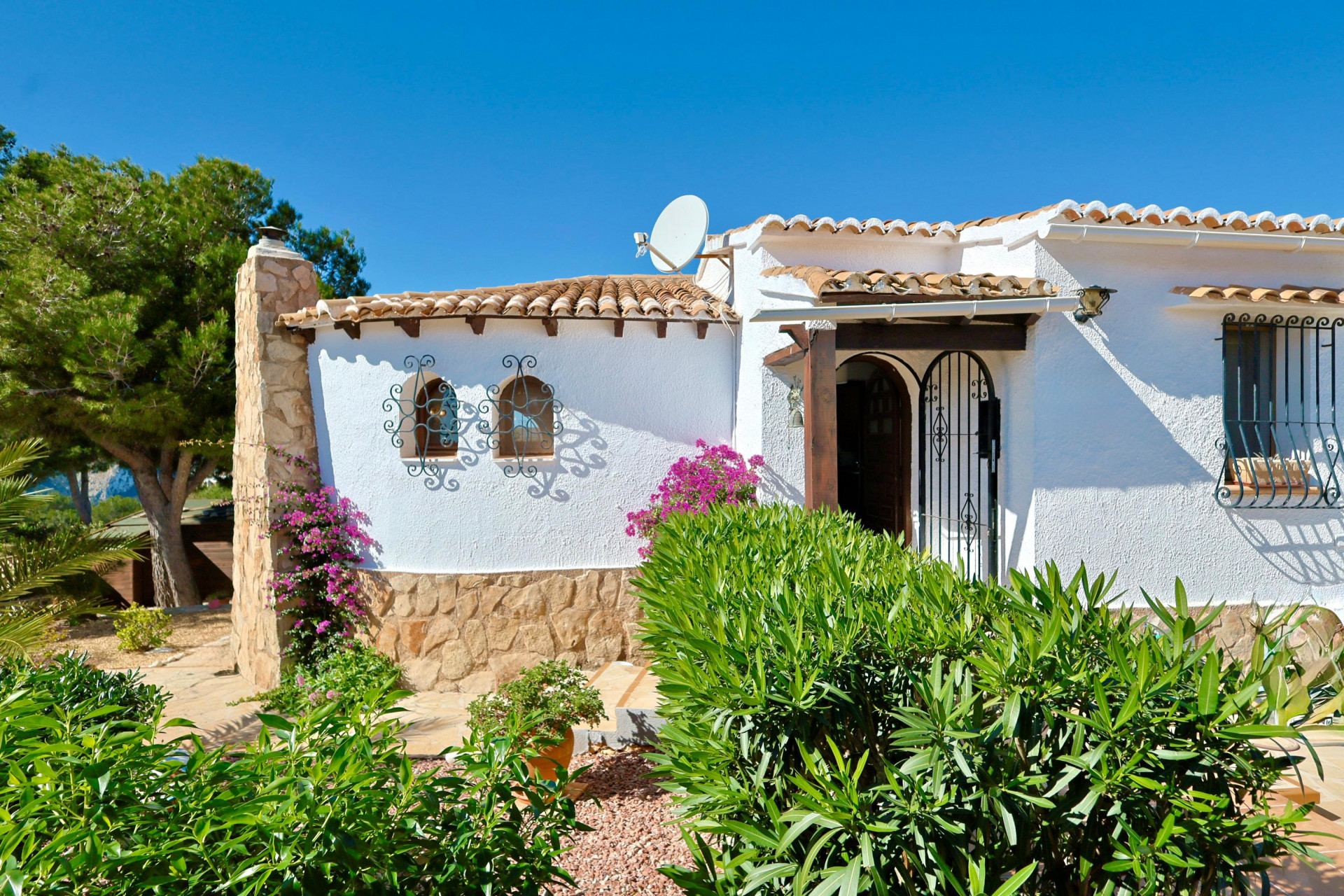 Façade d'une villa méditerranéenne avec détails en pierre, tuiles et ferronneries ornementales.