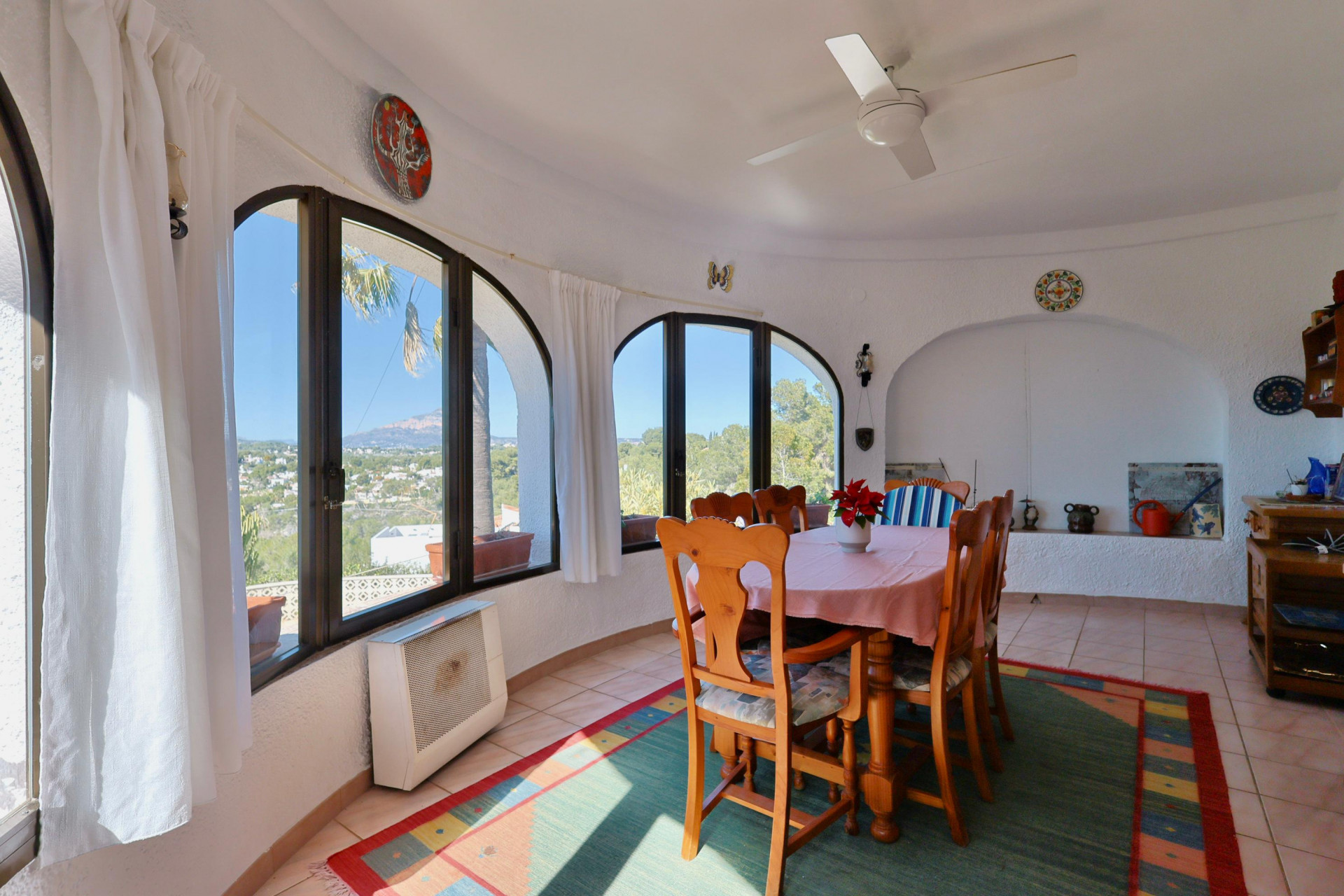 Salle à manger lumineuse avec fenêtres cintrées offrant une vue panoramique sur Jávea.