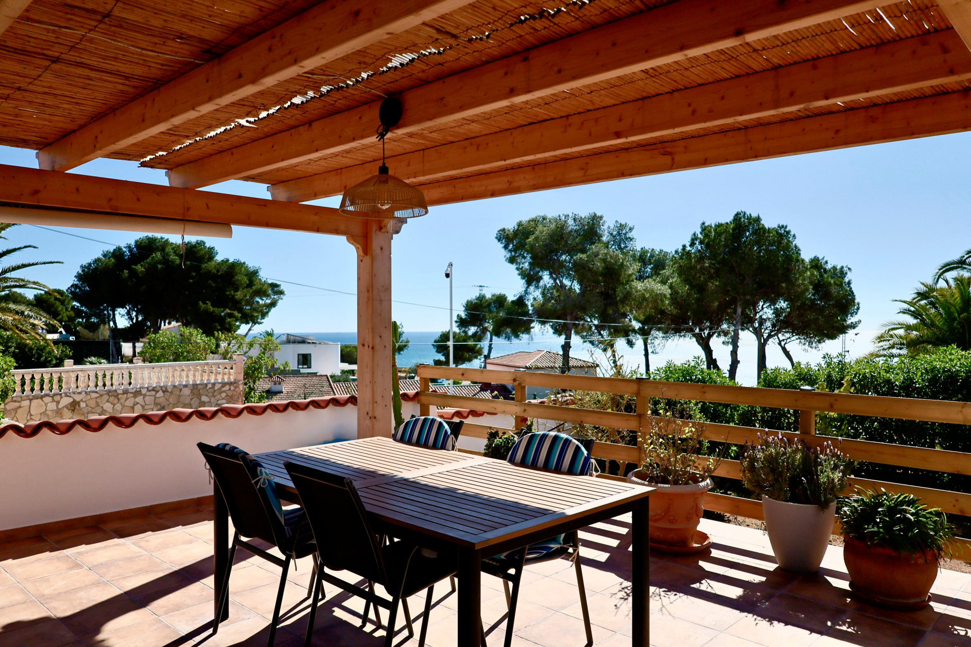 Terrasse couverte avec table à manger et vue sur la mer à Jávea.