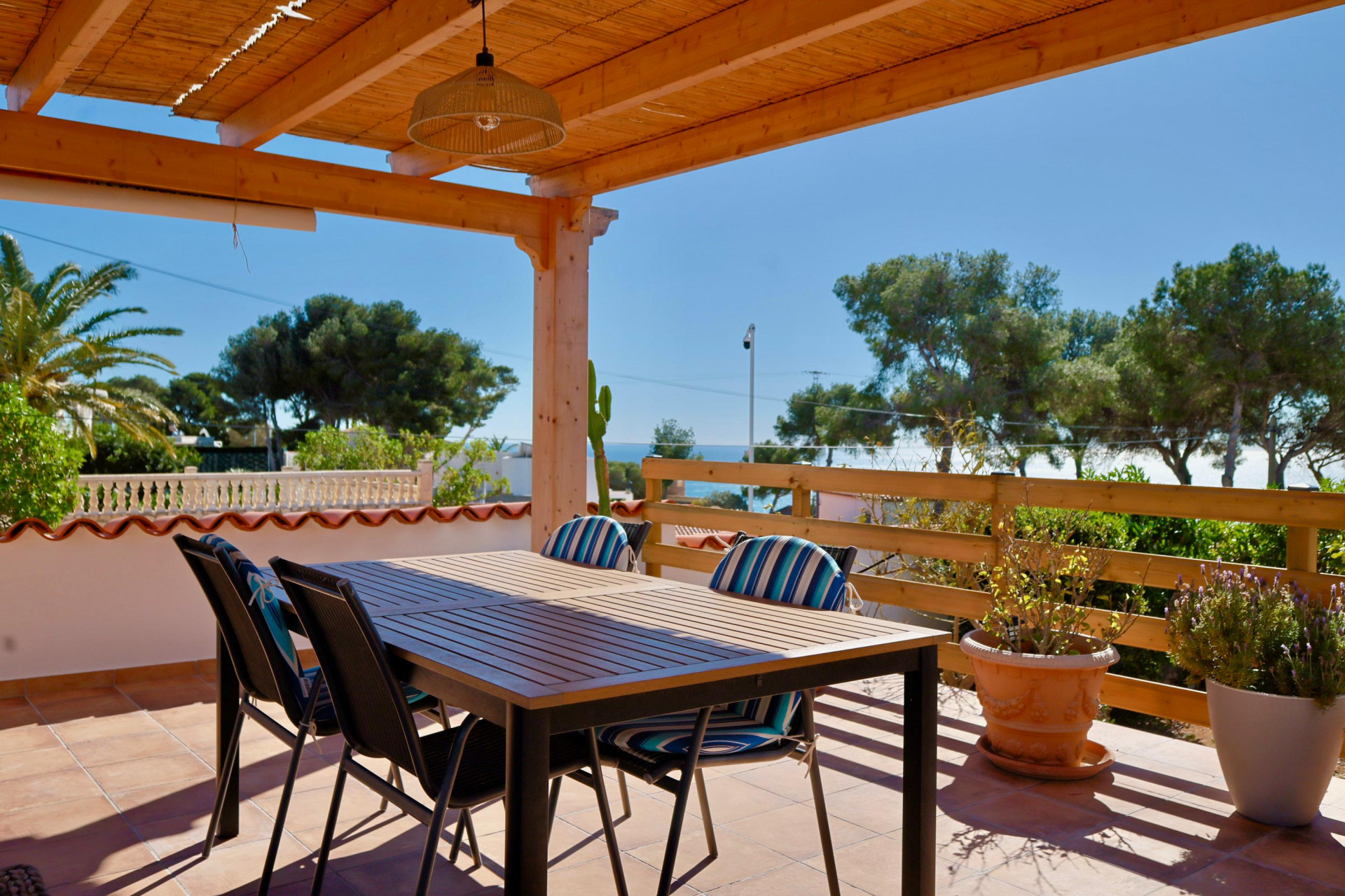 Terrasse couverte avec table à manger et vue sur la mer Méditerranée.