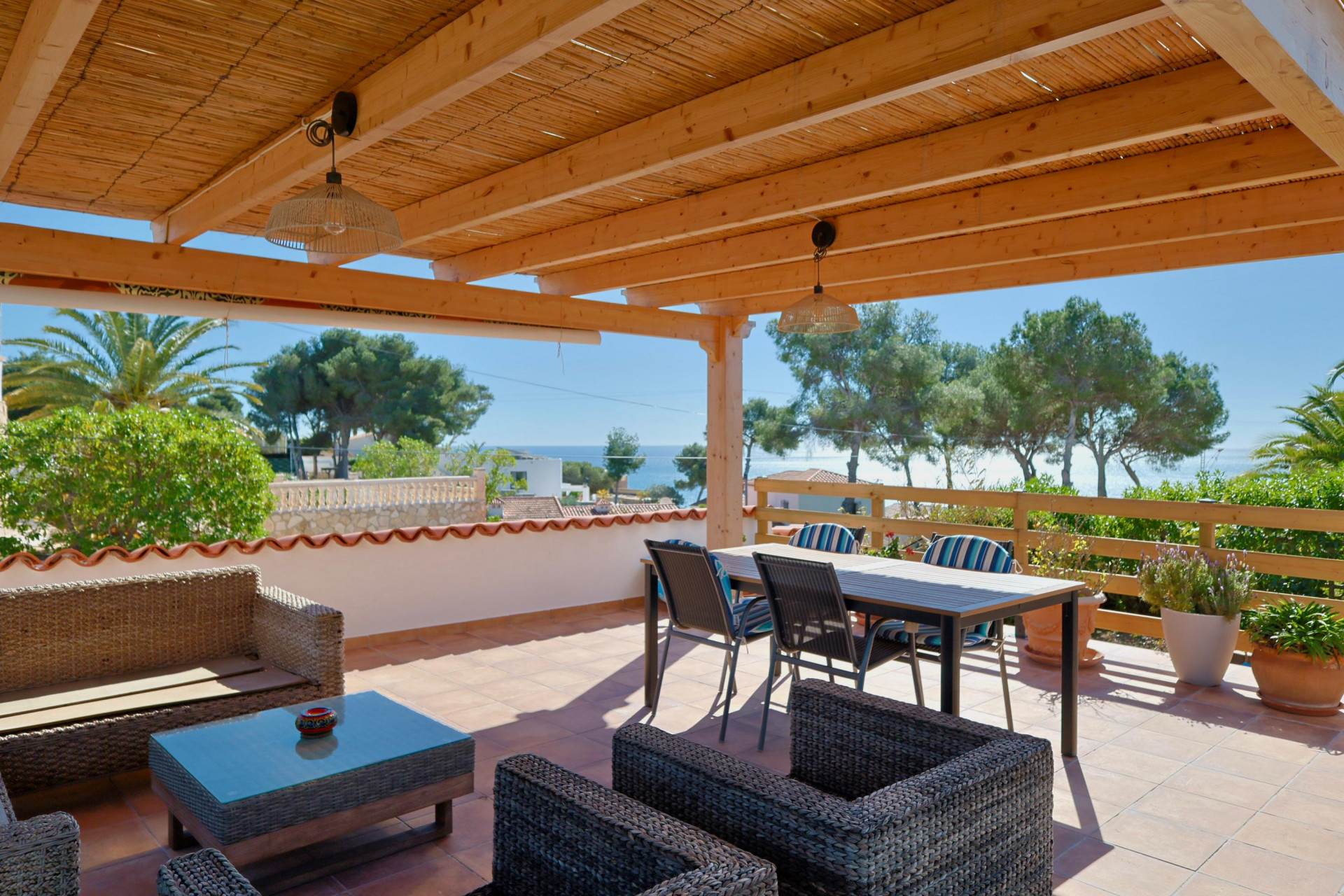 Terrasse couverte avec vue sur mer et mobilier en rotin.