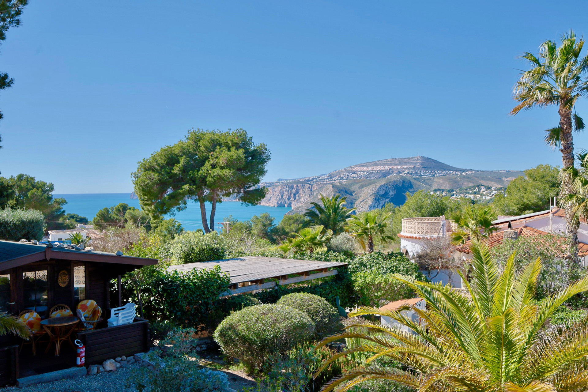 Vue panoramique de Jávea avec cabane en bois et végétation luxuriante.