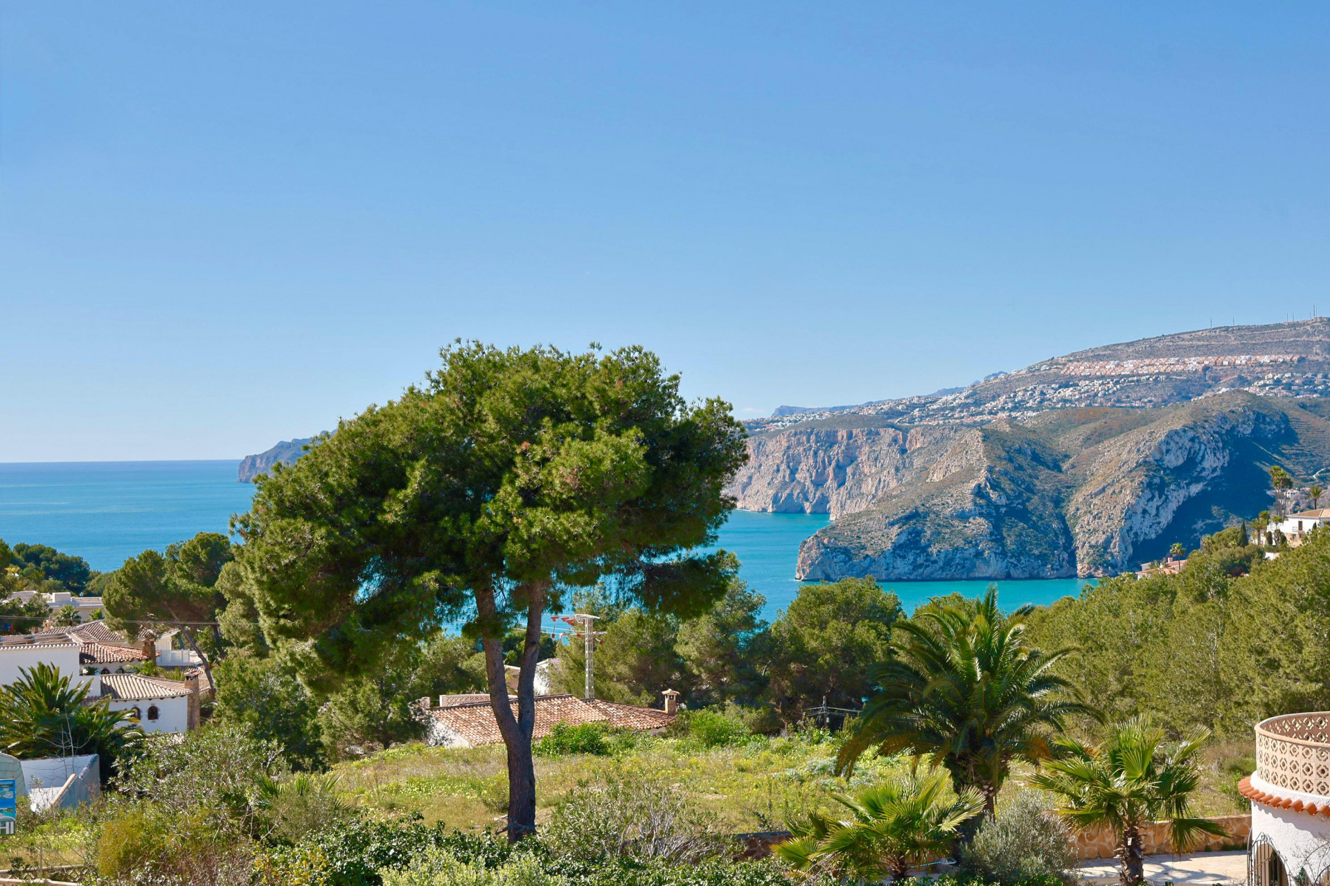 Vue panoramique de Jávea avec une végétation luxuriante et la mer Méditerranée en arrière-plan.