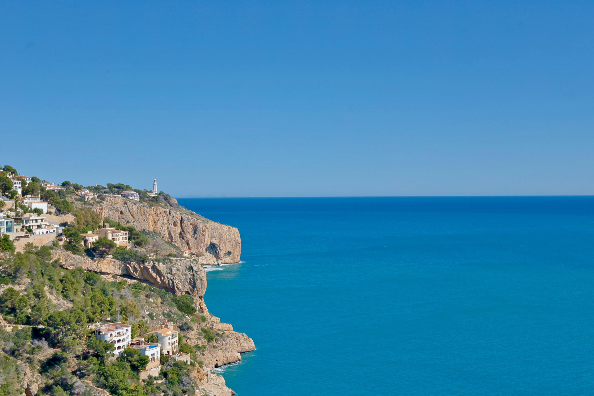 Vue panoramique de la côte rocheuse et de la mer Méditerranée depuis Jávea, avec des maisons blanches à flanc de colline.