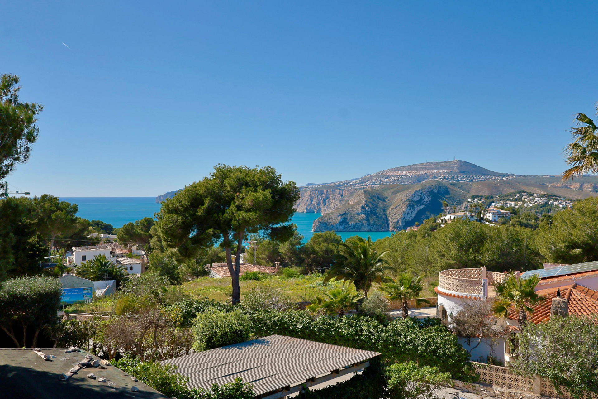Vue panoramique sur la côte et la montagne de Jávea depuis la terrasse, avec végétation méditerranéenne.