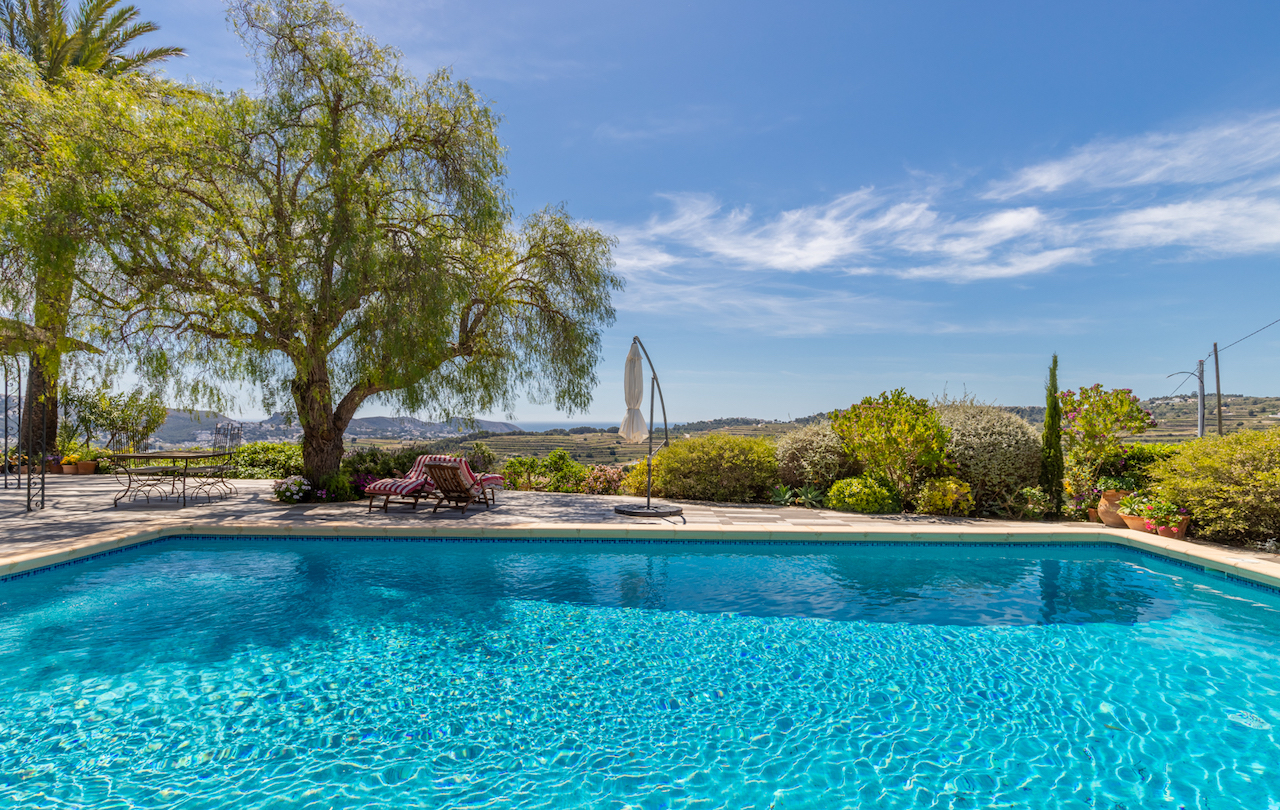 Terrasse de piscine spacieuse avec pavage antidérapant, coin salon ombragé et vues panoramiques sur les vignobles et la mer Méditerranée.