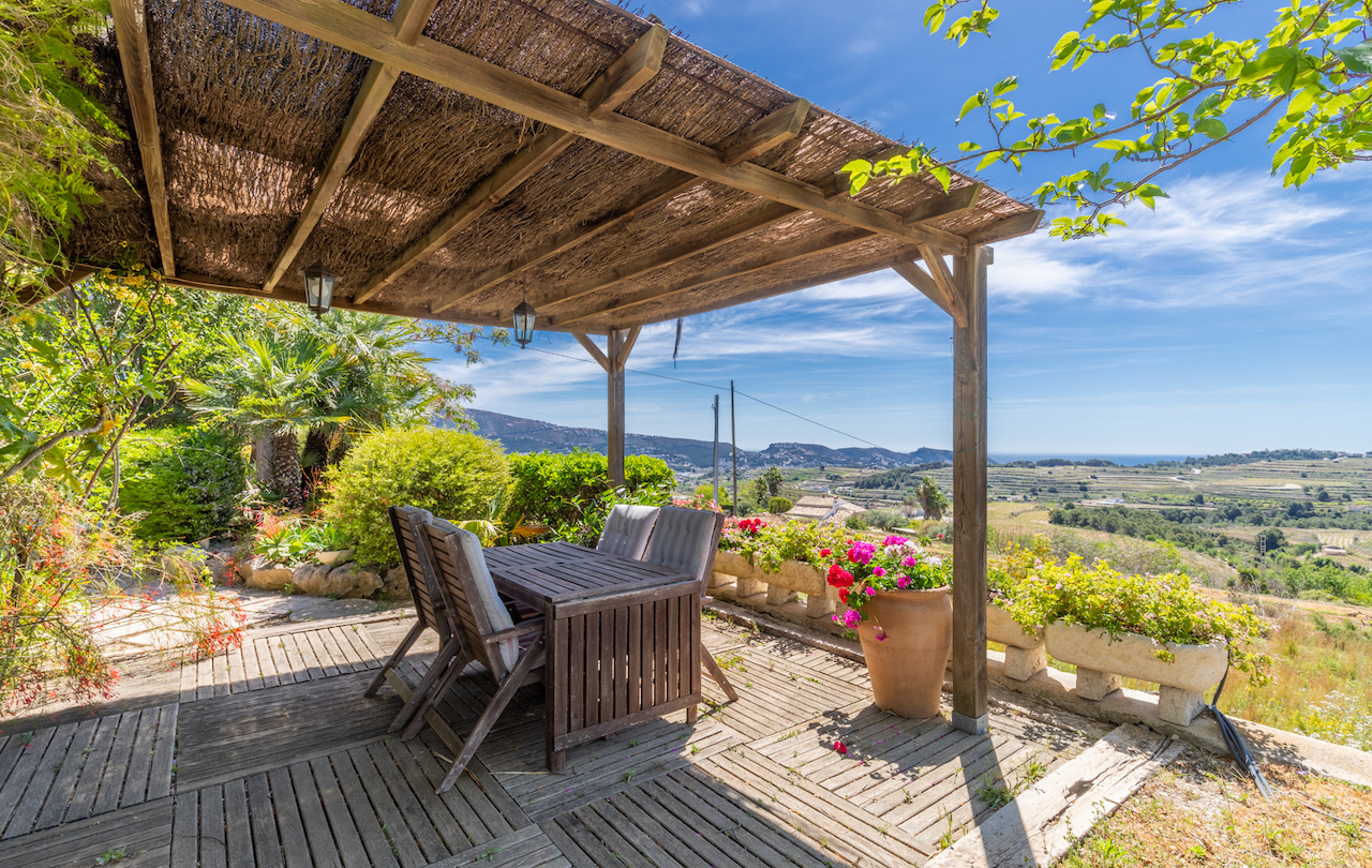 Terrasse extérieure avec pergola en bois et bruyère, espace dînatoire en teck et vue panoramique sur les vignobles et la mer Méditerranée.