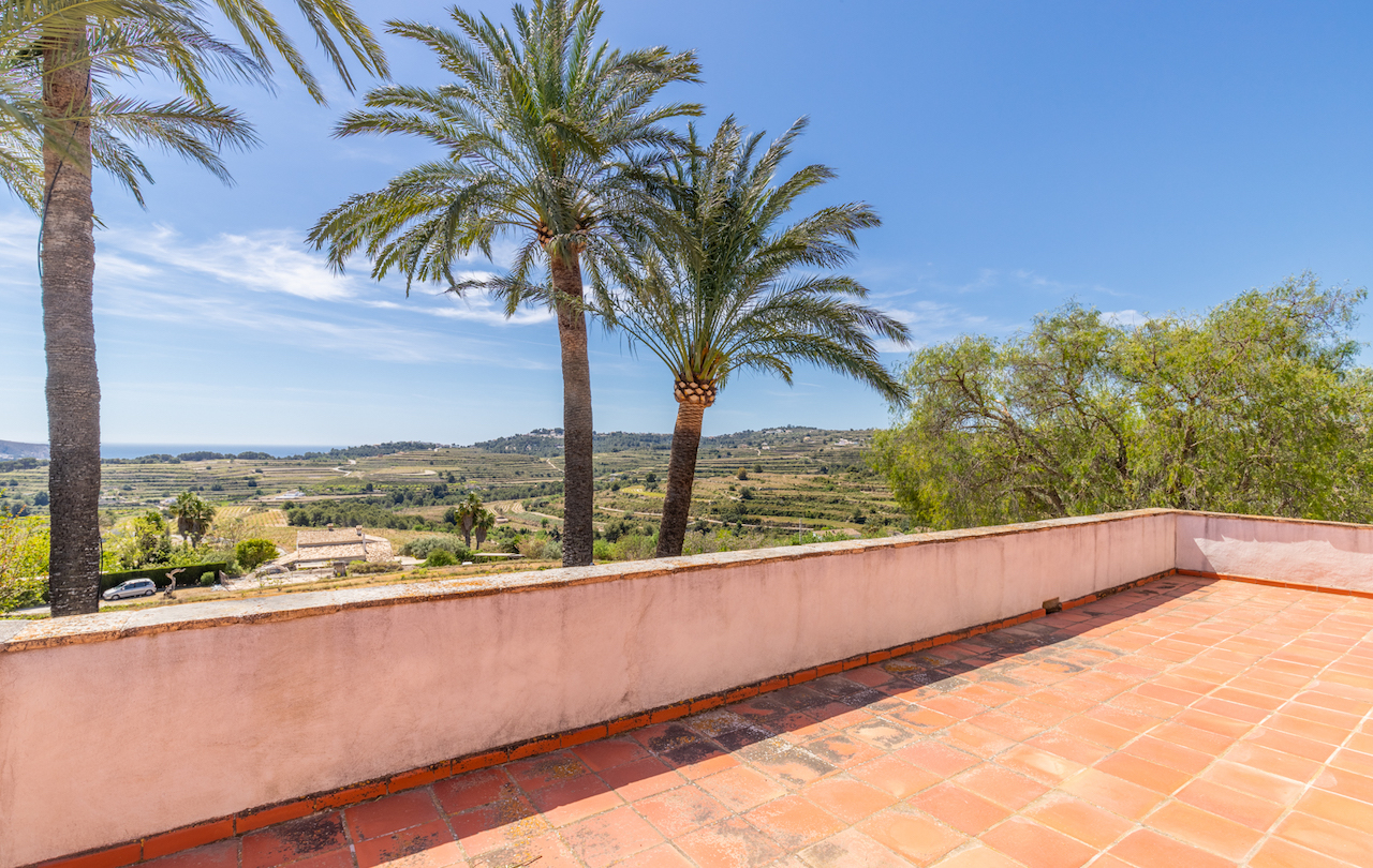 Terrasse surélevée avec revêtement en terre cuite, offrant une vue panoramique sur les vignobles en terrasses et la mer Méditerranée au loin.