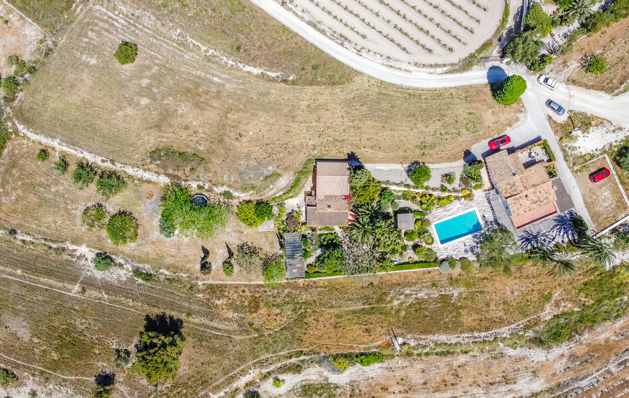 Vue aérienne de la propriété montrant la disposition des deux maisons, la piscine avec terrasse et les jardins matures intégrés au paysage rural.