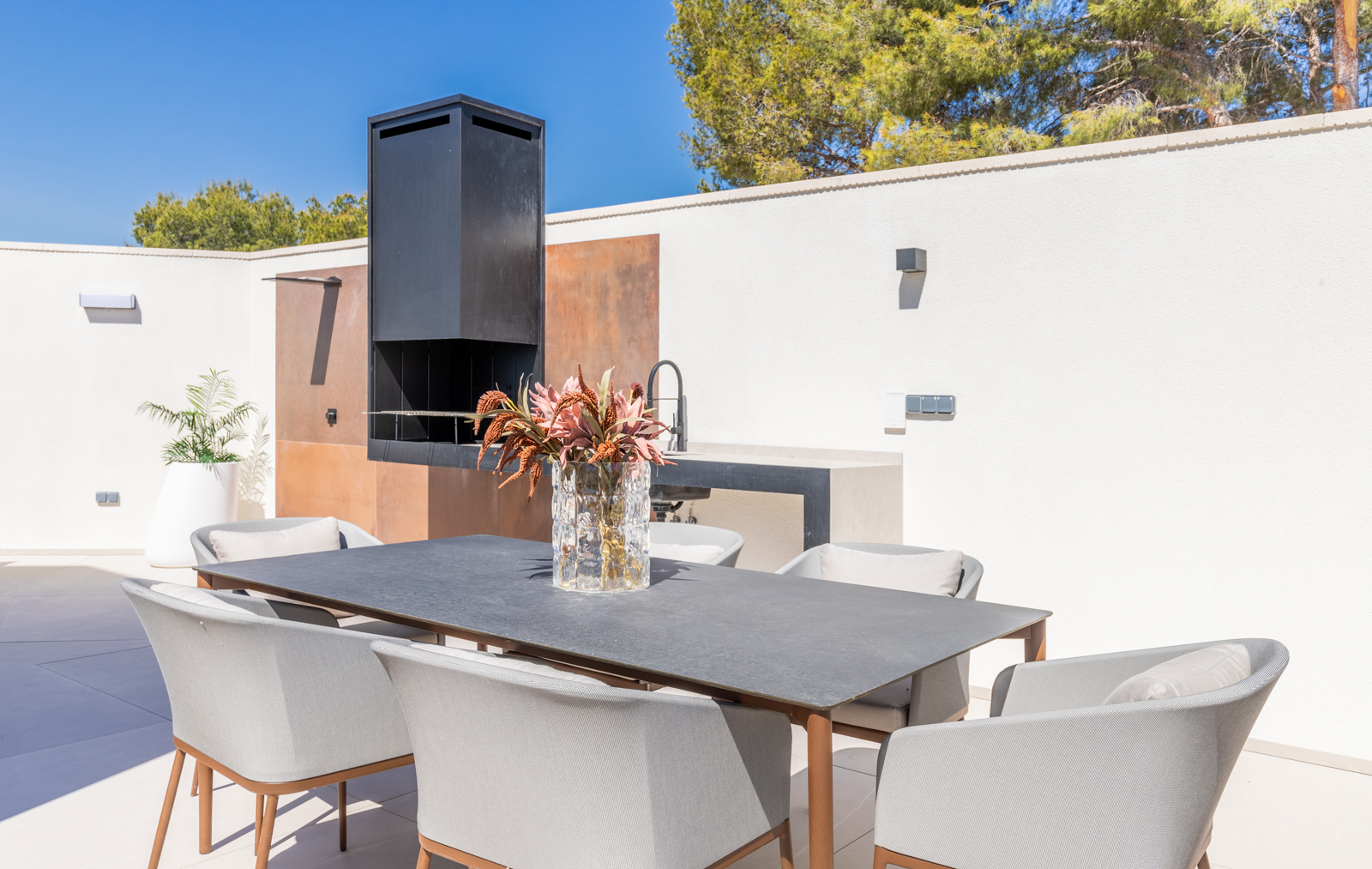 Détail de l'espace barbecue extérieur avec table à manger et chaises grises à La Nucia.