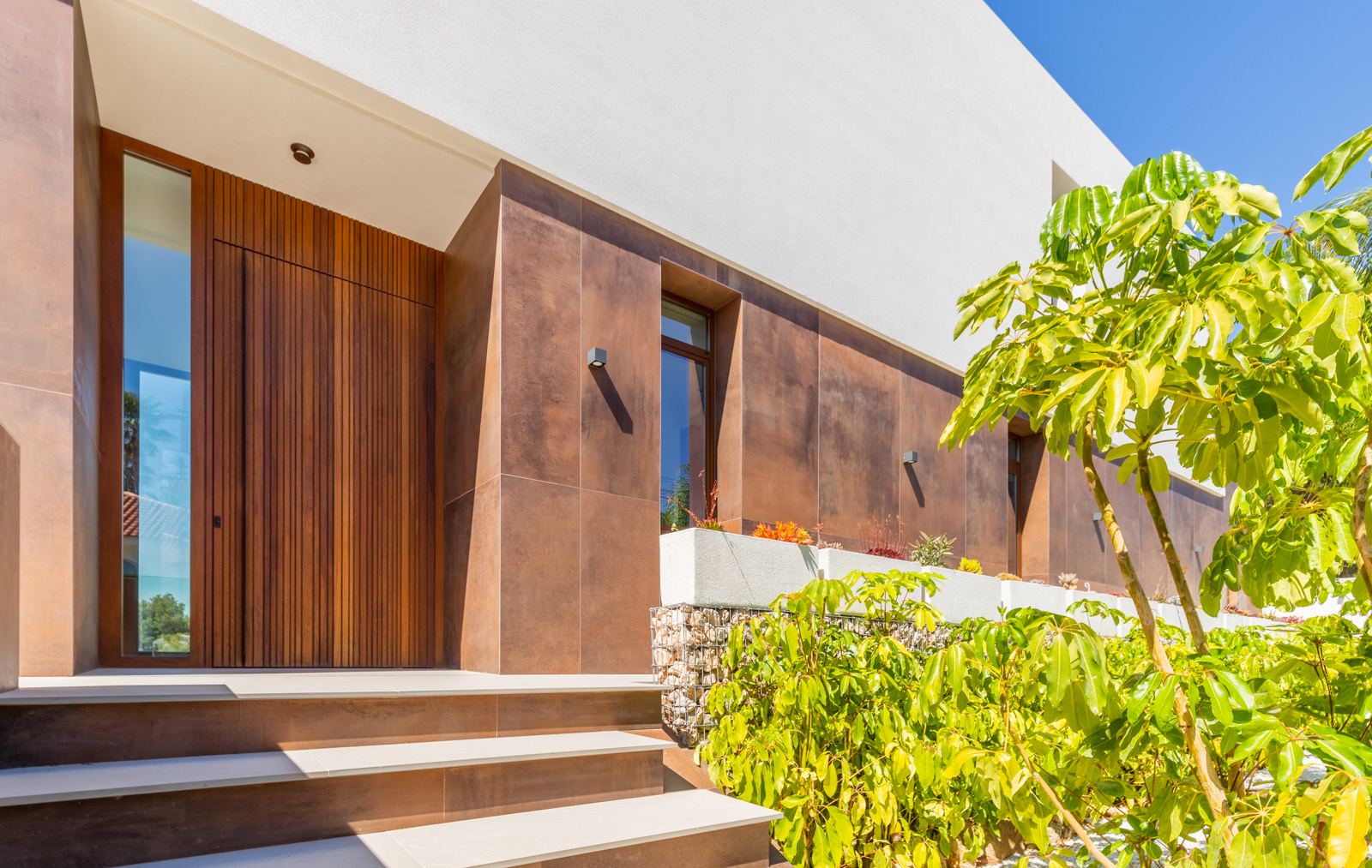 Entrée moderne avec porte en bois verticale et revêtement céramique couleur rouille.