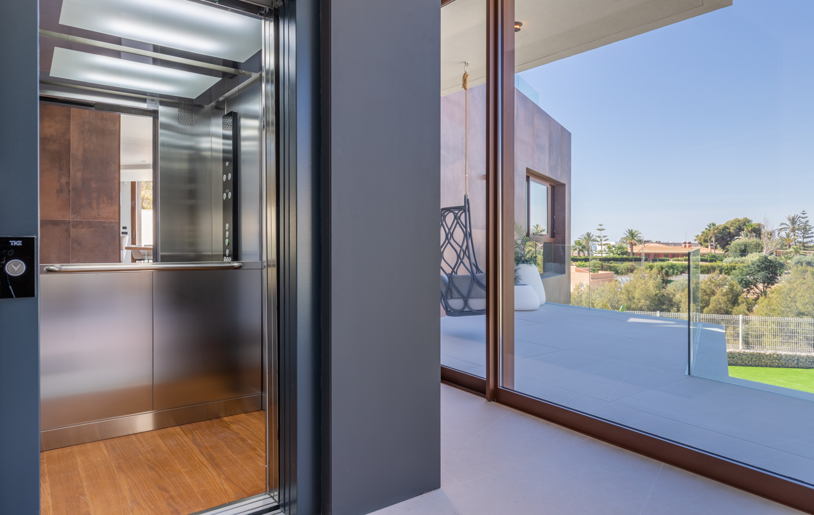 Intérieur avec ascenseur en acier inoxydable et terrasse avec vue sur le paysage.