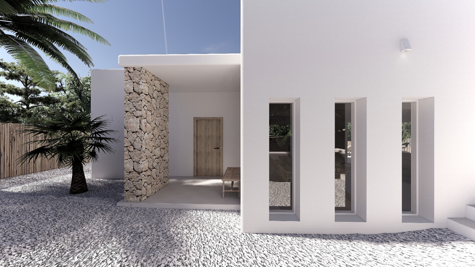 Entrée principale avec façade blanche, mur en pierre naturelle et fenêtres verticales. Le sol en gravier blanc et la végétation méditerranéenne soulignent le style épuré.