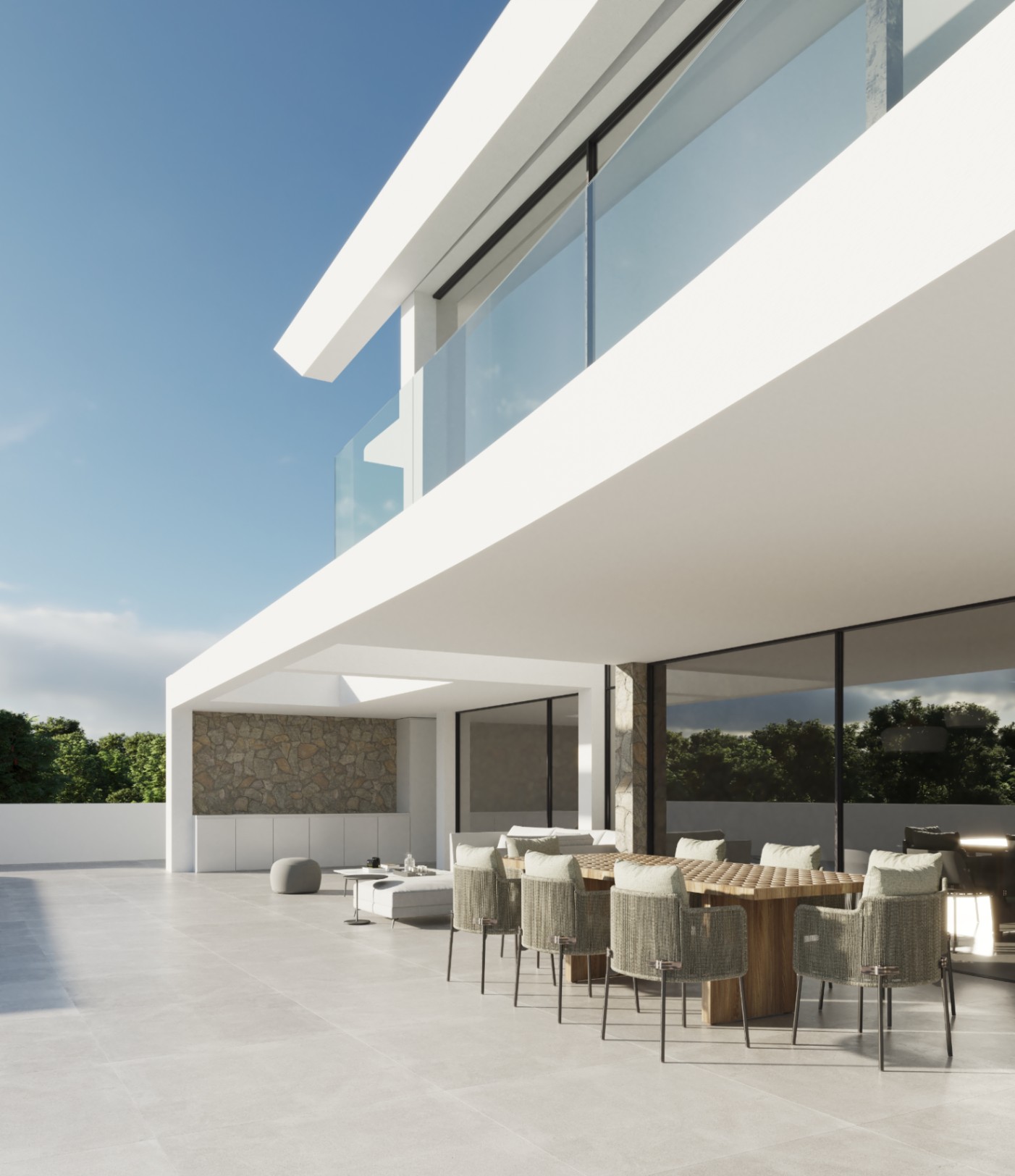 Terrasse extérieure avec salle à manger en bois et chaises tressées, soulignée par une architecture minimaliste blanche, des murs en pierre et des garde-corps en verre.