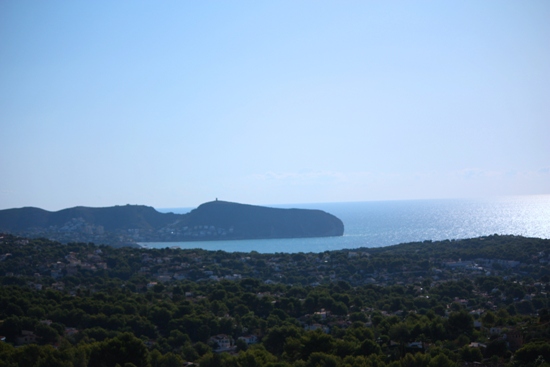 Vue panoramique depuis la propriété sur la mer Méditerranée et le cap de Moraira, entourée d'une pinède dense et de zones résidentielles.