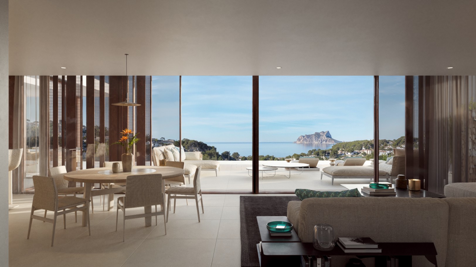Salon-salle à manger ouvert avec de grandes baies vitrées offrant une vue panoramique sur la mer et le Peñón de Ifach, liant l'intérieur à la terrasse.