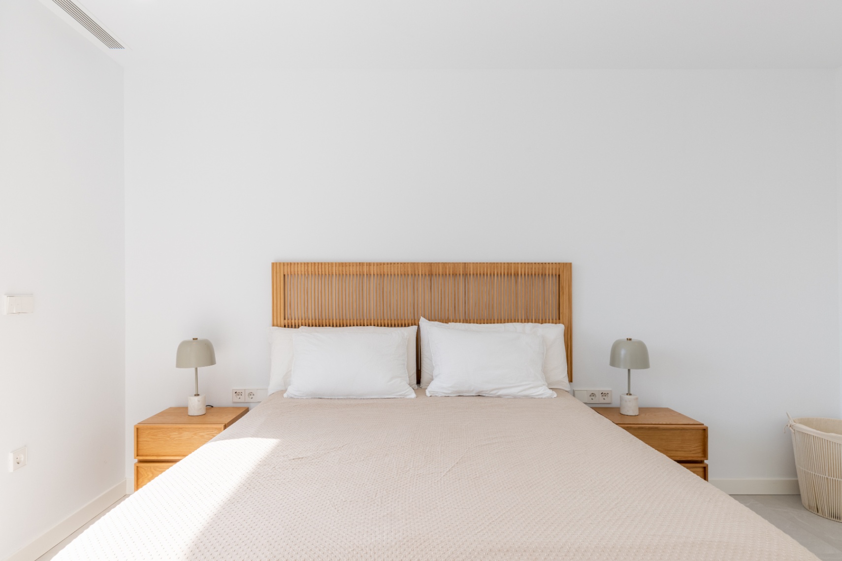 Chambre lumineuse avec tête de lit en bois et tables de chevet assorties.