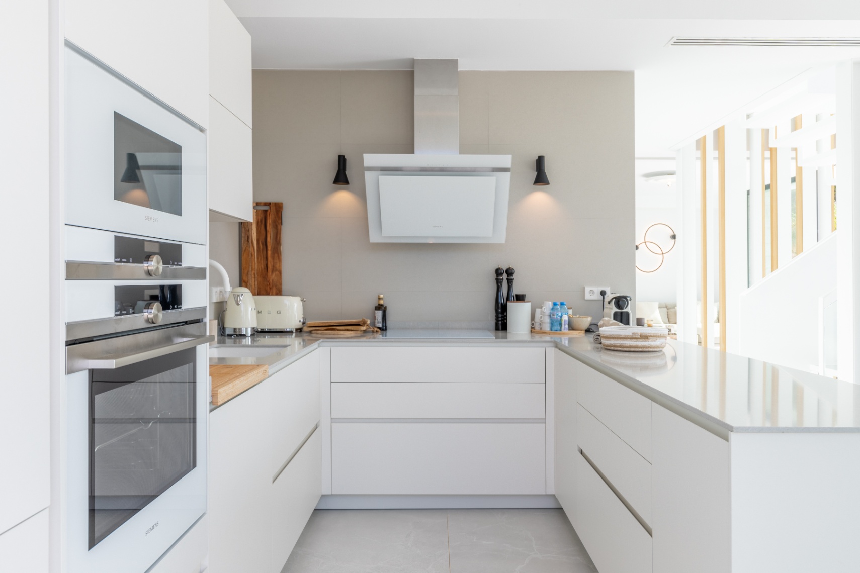 Cuisine moderne avec appareils Siemens, plans de travail en pierre claire et hotte aspirante minimaliste.