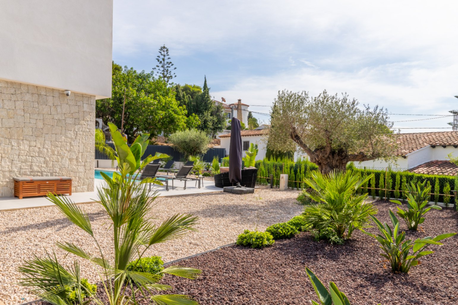 Jardin méditerranéen avec gravier, piscine et chaises longues à La Fustera, Benissa.