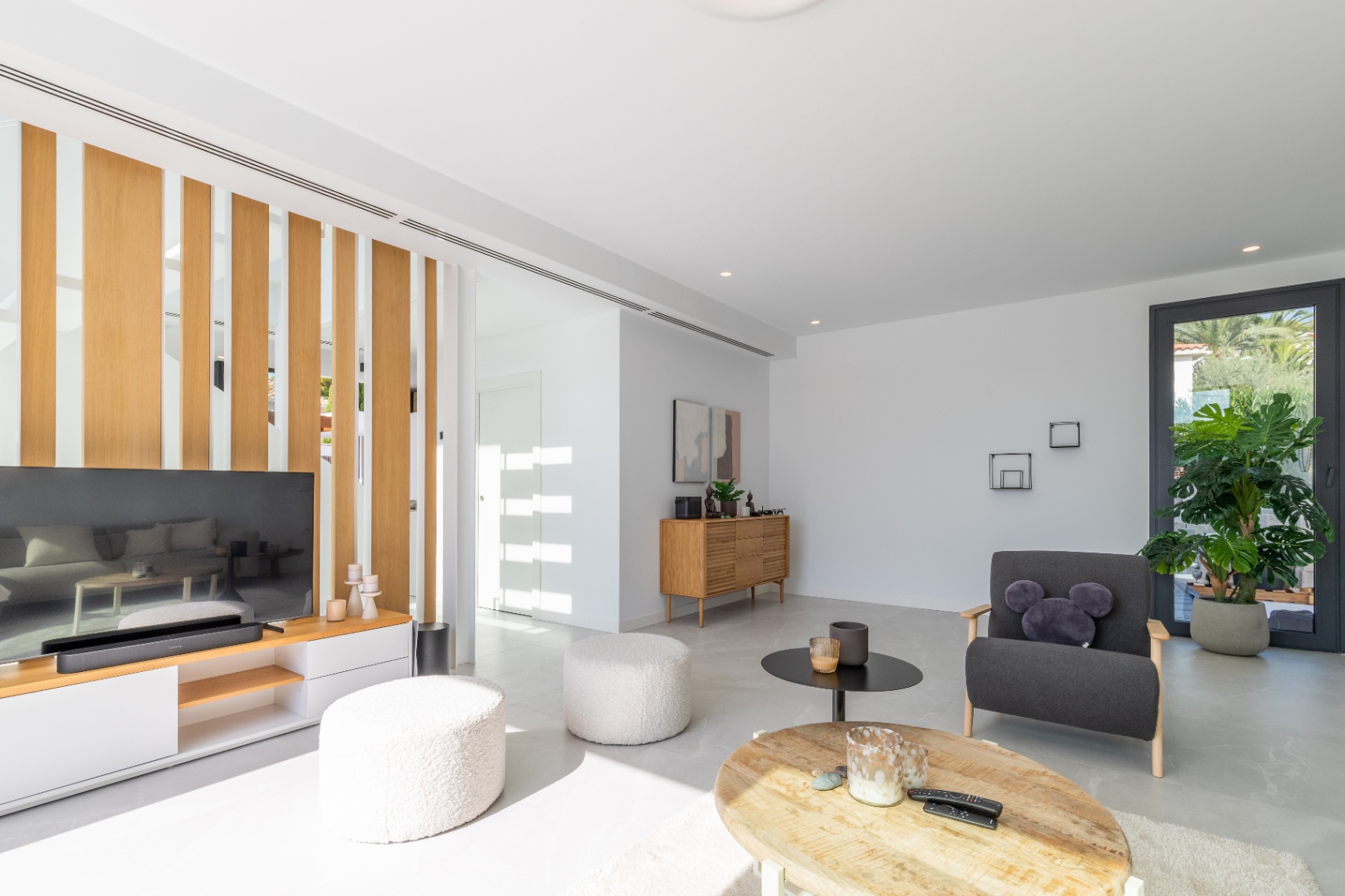 Salon lumineux avec séparateur en bois, mobilier moderne et touches de design minimaliste.