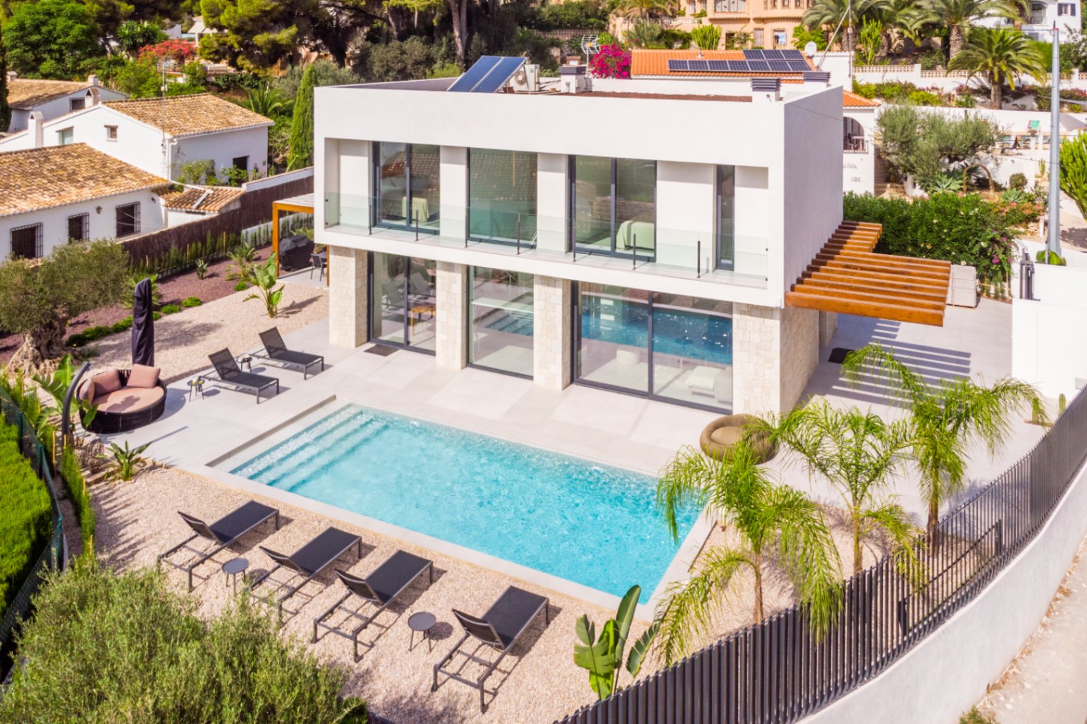 Vue aérienne de la villa avec piscine turquoise, entourée de transats et de gravier clair.