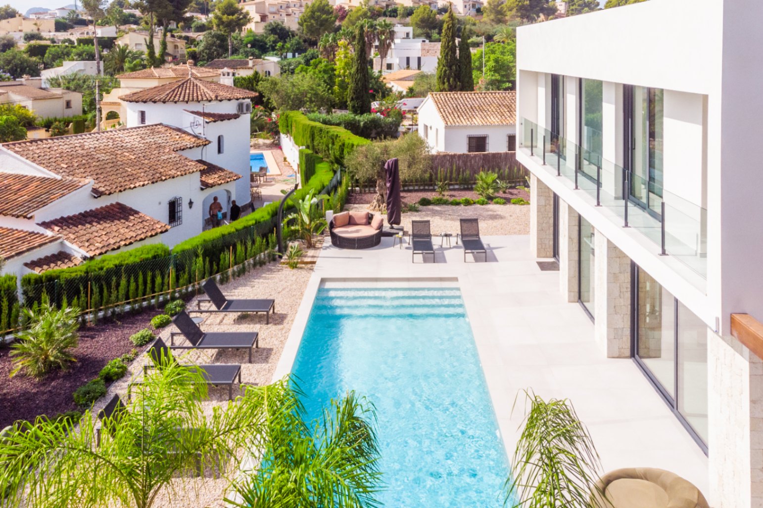 Vue élevée de la piscine rectangulaire avec transats noirs et jardin de gravier.