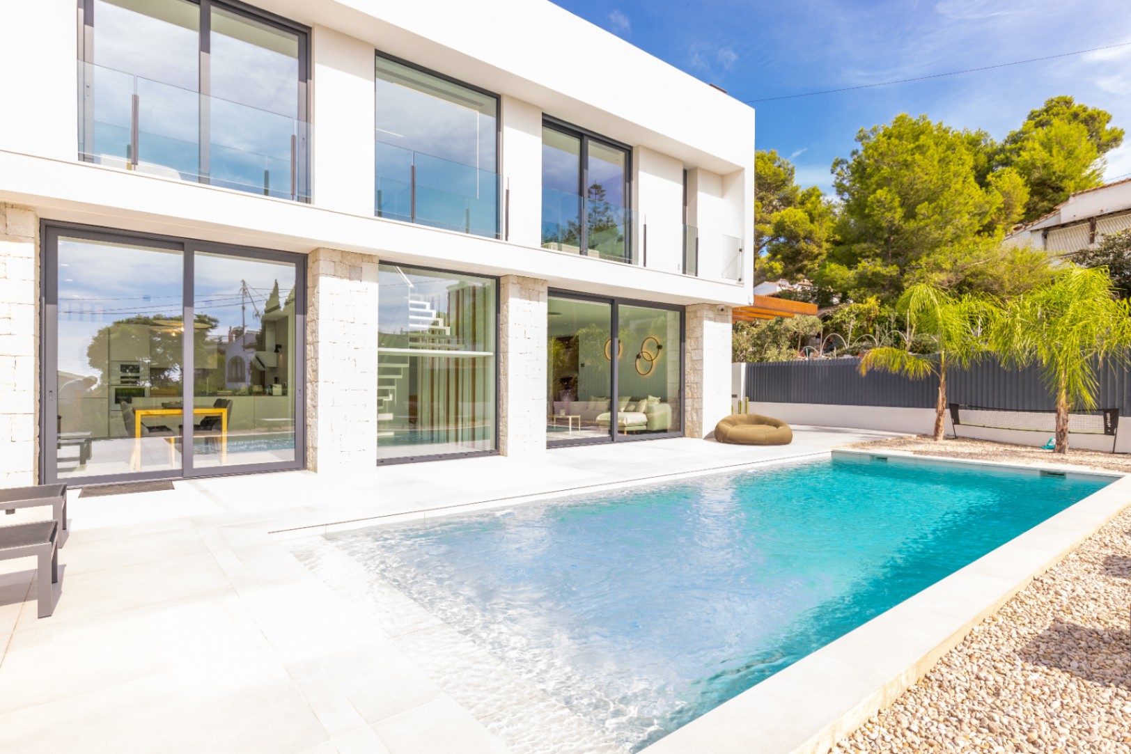 Vue sur la piscine privée, la terrasse carrelée et la façade moderne de la villa à Benissa.