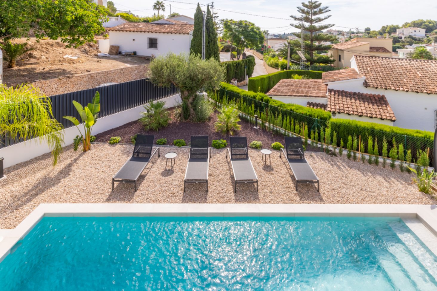 Vue surélevée de la piscine avec chaises longues, gravier et jardin de haies à Benissa.