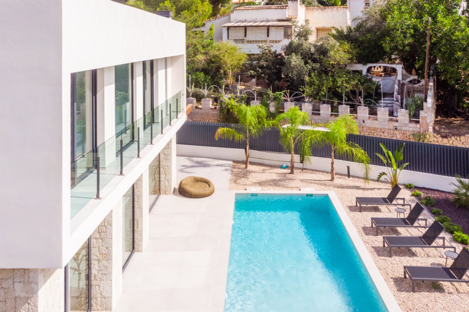Vue surélevée de la piscine privée avec chaises longues et jardin de gravier avec jeunes palmiers.