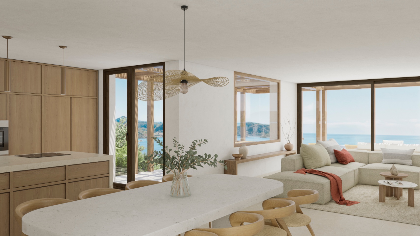 Intérieur lumineux avec cuisine ouverte, îlot en pierre et vue sur l'océan.