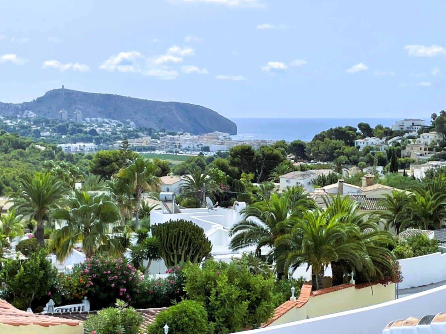 Vues panoramiques sur la côte de Moraira, la mer Méditerranée et le Cap d'Or, entourées d'une végétation méditerranéenne luxuriante et de palmiers.