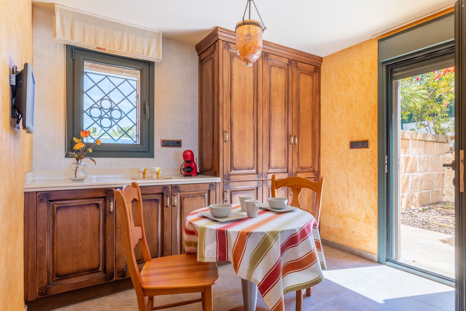 Cuisine rustique avec table ronde couverte et armoires en bois foncé.