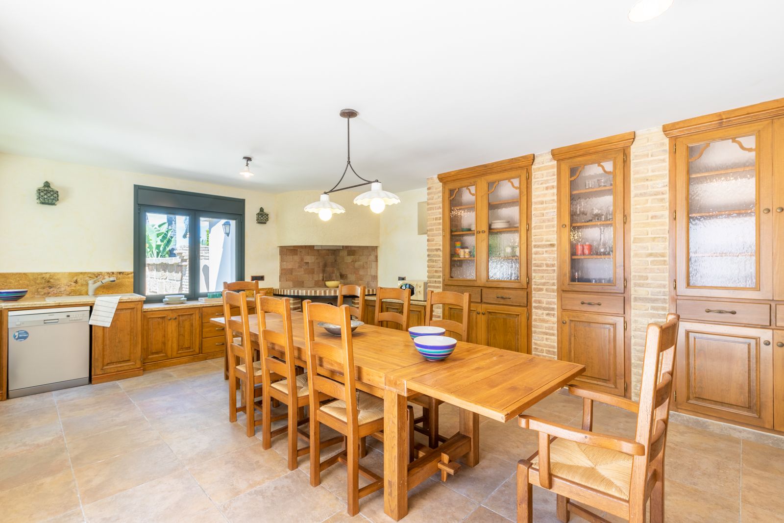 Salle à manger avec table en bois massif et buffet intégré en briques apparentes.