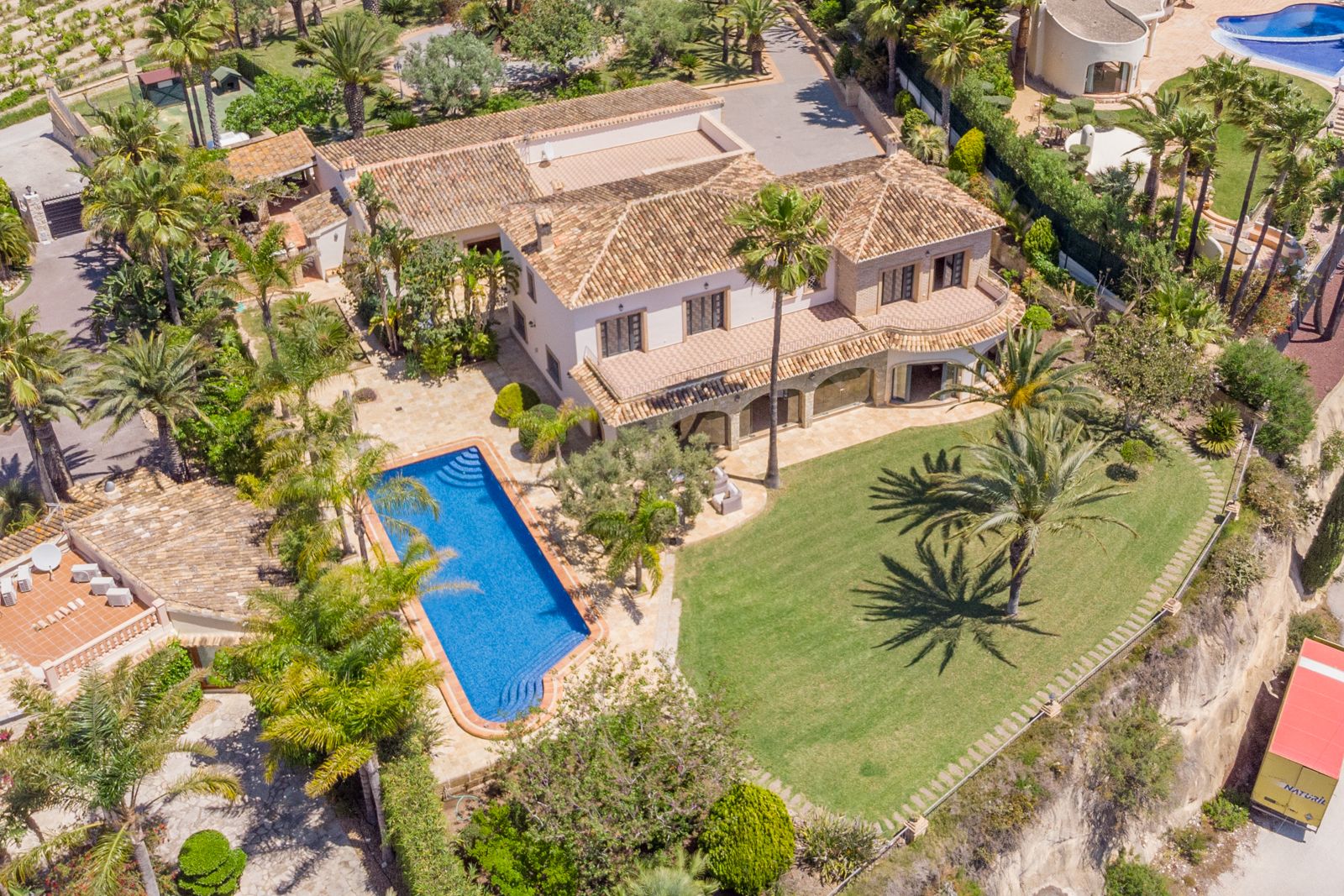 Vue aérienne du domaine avec piscine bleue, jardins matures et architecture méditerranéenne.
