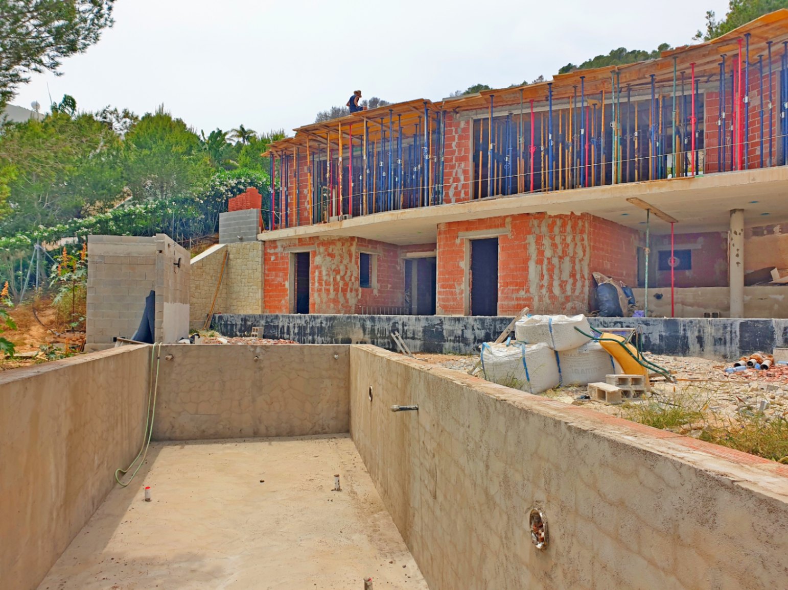 État actuel des travaux montrant la structure en briques sur deux niveaux, les étais métalliques et le bassin en béton de la piscine.