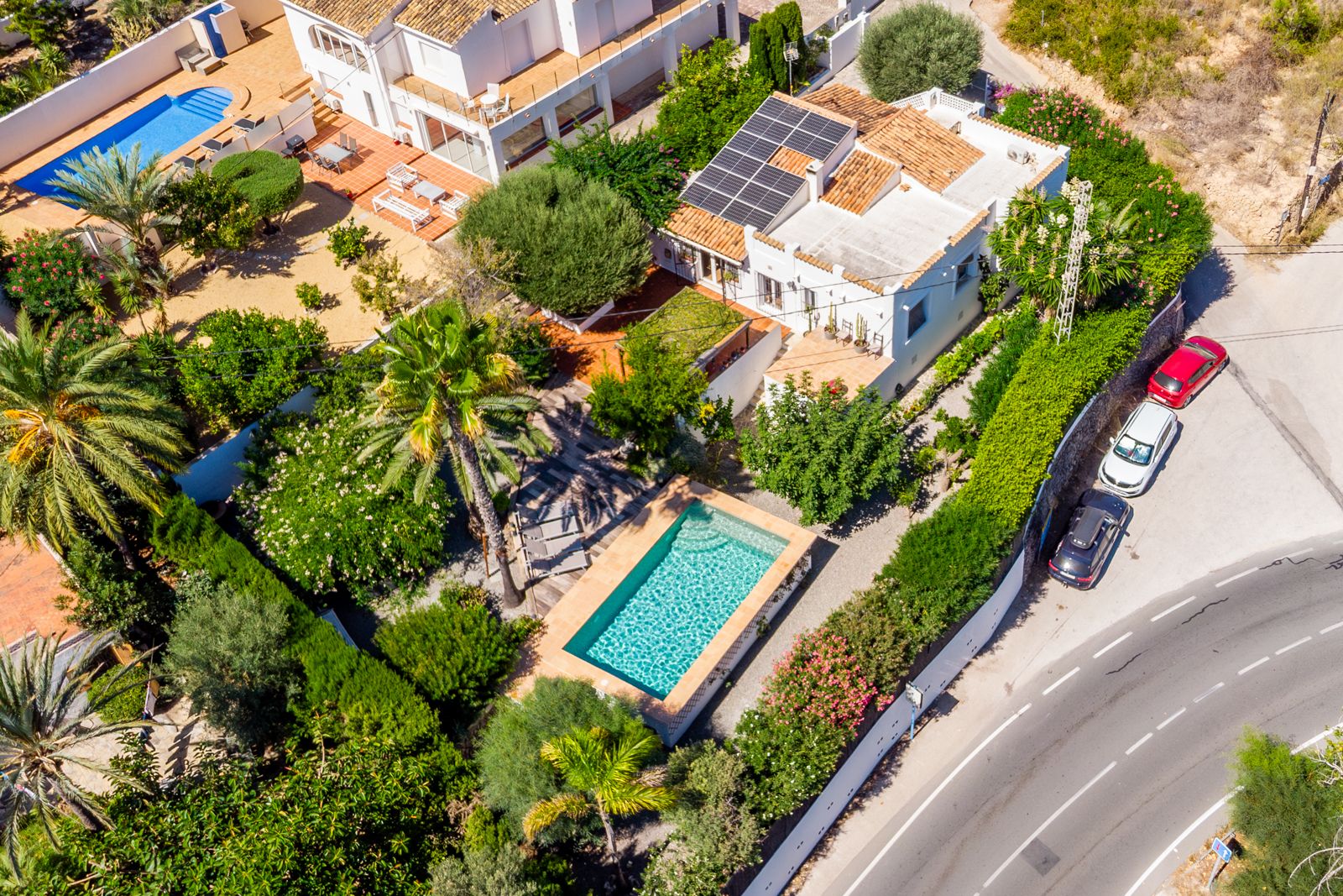 Vue aérienne de la villa mettant en valeur la piscine rectangulaire, le jardin méditerranéen luxuriant et les panneaux solaires sur le toit en tuiles.