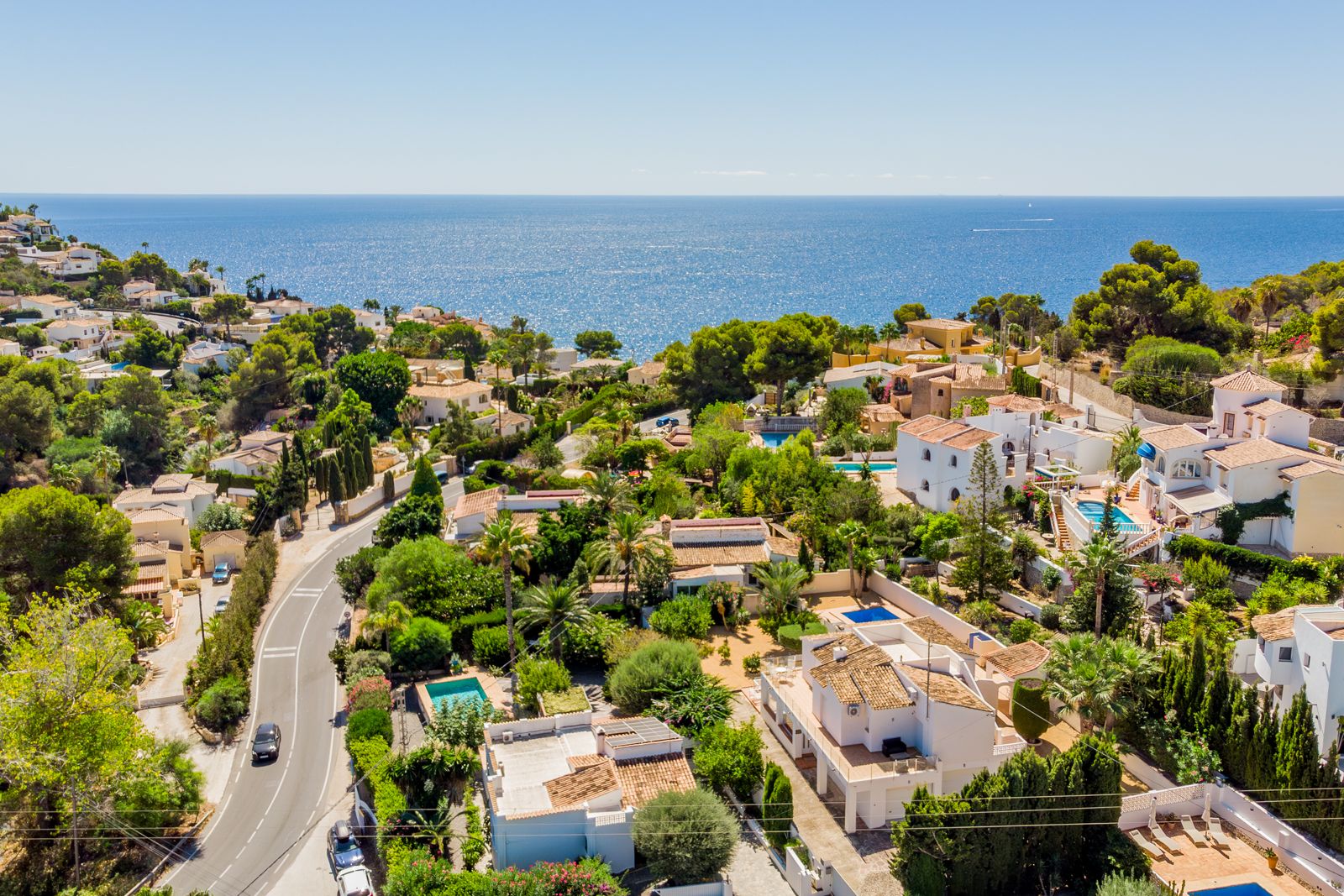 Vue aérienne panoramique de la zone côtière de Baladrar, soulignant la proximité de la Méditerranée et le paysage verdoyant de villas traditionnelles.