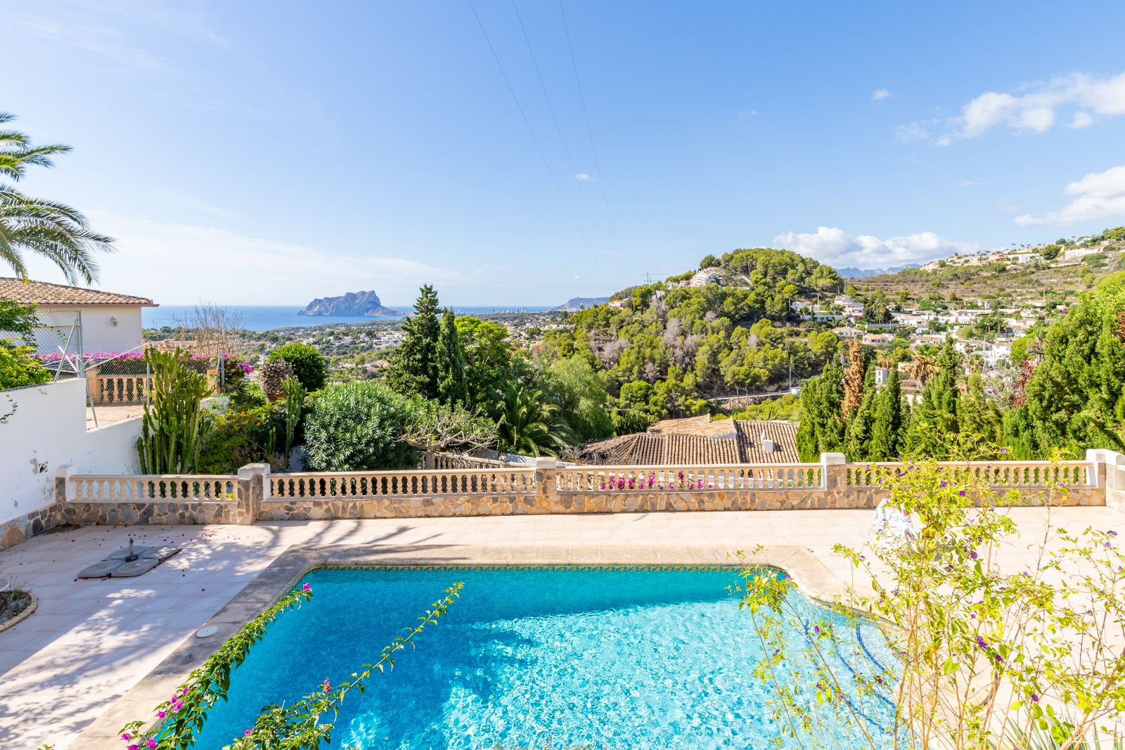 Espace piscine privée avec terrasse en pierre et balustrade, offrant une vue panoramique sur la mer Méditerranée et le célèbre rocher d'Ifach.
