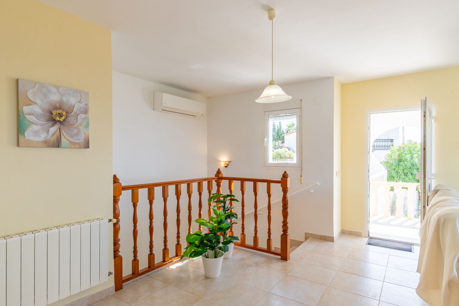 Palier lumineux avec sol en grès cérame, balustrade en bois tourné et accès terrasse. Équipé d'une climatisation réversible et d'un radiateur de chauffage central.
