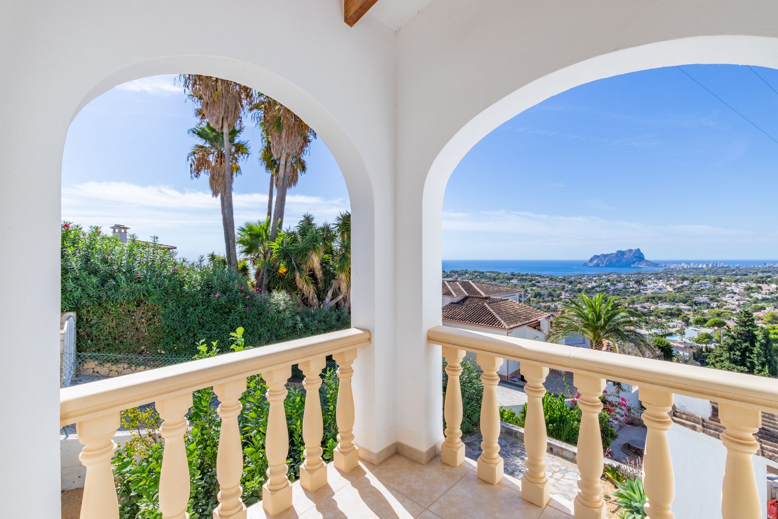 Terrasse couverte avec arches blanches et balustrade classique, offrant une vue panoramique sur la mer Méditerranée et le Peñón de Ifach.